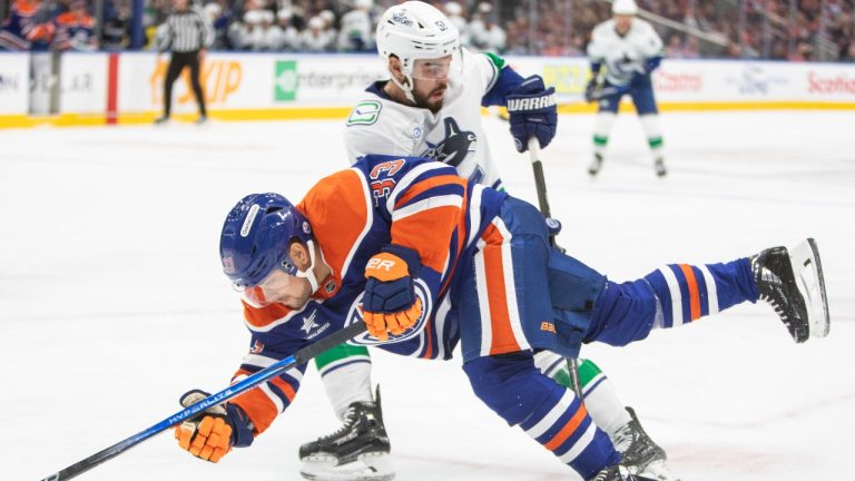 Vancouver Canucks Mark Friedman (51) looks for the puck as Edmonton Oilers Viktor Arvidsson (33) falls during second period NHL pre-season action in Edmonton on Monday September 30, 2024.  (Amber Bracken/CP)