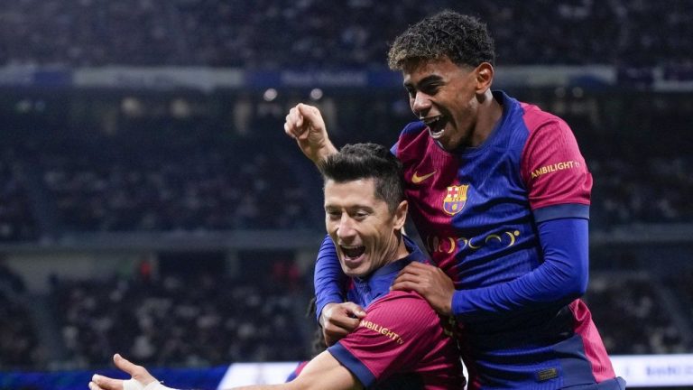 Barcelona's Robert Lewandowski celebrates after scoring his side's second goal with Lamine Yamal, right, during a Spanish La Liga soccer match between Real Madrid and Barcelona at the Santiago Bernabeu stadium in Madrid, Spain, Saturday, Oct. 26, 2024. (Manu Fernandez/AP Photo)
