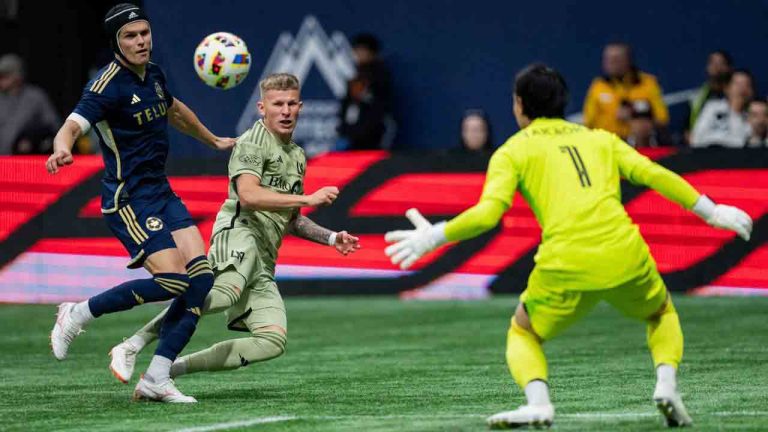 Los Angeles FC's Mateusz Bogusz, centre, scores on Vancouver Whitecaps goalkeeper Yohei Takaoka, right, as Bjorn Inge Utvik, left, defends during the first half of an MLS soccer match in Vancouver, B.C., Sunday, Oct. 13, 2024. (Ethan Cairns/CP)