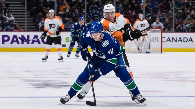 Vancouver Canucks' Elias Pettersson, front, of Sweden, reaches for the puck in front of Philadelphia Flyers' Cam Atkinson during the third period of an NHL hockey game. (Darryl Dyck/THE CANADIAN PRESS)