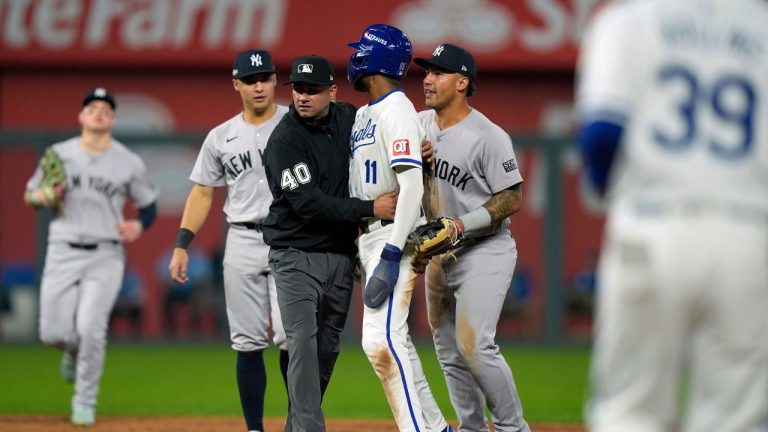 Umpire Roberto Ortiz holds back Kansas City Royals' Maikel Garcia (11) after being tagged out by New York Yankees shortstop Anthony Volpe as the benches empty after a double play during the sixth inning in Game 4 of an American League Division baseball playoff series Thursday, Oct. 10, 2024, in Kansas City, Mo. (Charlie Riedel/AP Photo)