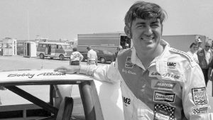 Bobby Allison stands beside his car and talks with the press after winning the pole position during qualifying for the 500 mile grand national stock car race at Pocono Raceway, Aug. 2, 1975, in Long Pond, Pa. (AP Photo)