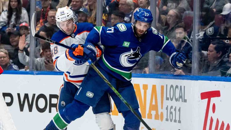 Edmonton Oilers' Luke Philp (48) and Vancouver Canucks' Derek Forbort (27) vie for the puck during third period NHL pre-season hockey action in Vancouver, on Friday, October 4, 2024. (Ethan Cairns/CP)