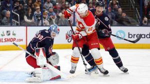 Columbus Blue Jackets goalie Elvis Merzlikins, left, makes a stop in front of Calgary Flames forward Jonathan Huberdeau, centre, and Blue Jackets defenceman Zach Werenski during the first period of an NHL hockey game in Columbus, Ohio, Friday, Nov. 29, 2024. (Paul Vernon/AP)