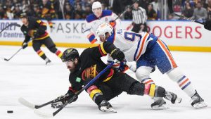 Vancouver Canucks' Conor Garland, front left, falls in front of Edmonton Oilers' Connor McDavid during the first period of an NHL hockey game in Vancouver, on Saturday, November 9, 2024. (Darryl Dyck/CP)