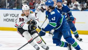 Chicago Blackhawks' Connor Bedard (98) and Vancouver Canucks' Quinn Hughes (43) vie for the puck during first period NHL hockey action in Vancouver, B.C., Saturday, Nov. 16, 2024. (Ethan Cairns/CP)