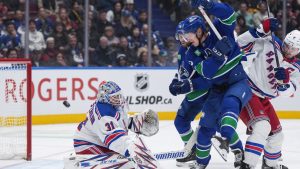 New York Rangers goalie Igor Shesterkin (31) makes the save as Vancouver Canucks' Aatu Raty, second right, watches while being checked by New York's Jacob Trouba (8) during first period NHL hockey action in Vancouver, B.C., Tuesday, Nov. 19, 2024. THE CANADIAN PRESS/Darryl Dyck