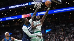 Boston Celtics guard Jaylen Brown, center right, drives toward the basket as Minnesota Timberwolves forward Julius Randle, center left, defends in the second half of an NBA basketball game, Sunday, Nov. 24, 2024, in Boston. (AP Photo/Steven Senne)