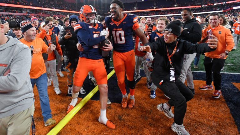 Syracuse quarterback Kyle McCord, left, celebrates with wide receiver Braden Davis as fans rushed the field after their win against Miami in an NCAA college football game on Saturday, Nov. 30, 2024 in Syracuse, N.Y. (AP Photo/Adrian Kraus)