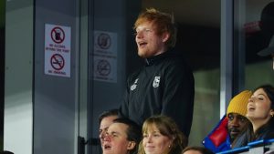 Ipswich Town fan Ed Sheeran, top, cheers for his team during the English Premier League soccer match between Ipswich Town and Manchester United at Portman Road stadium in Ipswich, England, Sunday, Nov. 24, 2024. (Dave Shopland/AP)