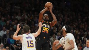 Phoenix Suns forward Kevin Durant shoots over Los Angeles Lakers guard Austin Reaves and forward Anthony Davis during the first half of an NBA game, Tuesday, Nov. 26, 2024, in Phoenix. (AP/Rick Scuteri)