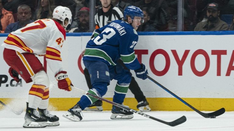 Vancouver Canucks' Jonathan Lekkerimaki (right) looks to make a pass while being pressured by Calgary Flames' Connor Zary. (Rich Lam/CP)