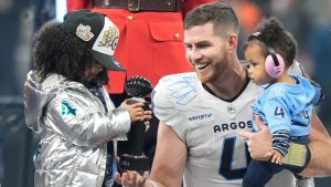 Toronto Argonauts quarterback Nick Arbuckle (4) passes the Most Valuable Player trophy to his daughter following the 111th Grey Cup in Vancouver, B.C., Sunday, Nov. 17, 2024. The Argonauts beat the Winnipeg Blue Bombers 41-24. THE CANADIAN PRESS/Frank Gunn