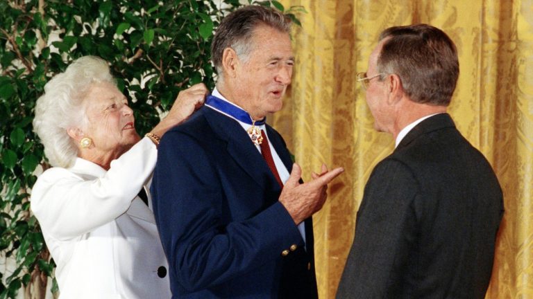 President George W. Bush, right, presents the Presidential Medal of Freedom to baseball great Ted Williams as Barbara Bush ties the medal around his neck Monday, Nov. 18, 1991, at a White House ceremony in Washington. (AP Photo/Marcy Nighswander)