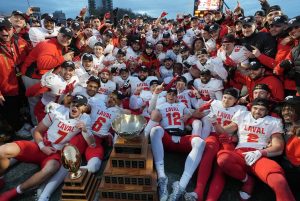 Laval University Rouge et Or players pose for photos with the trophy as they celebrate their win over Laurier Golden Hawks after U Sports Vanier Cup football action in Kingston, Ontario on Saturday, Nov. 23, 2024. (Frank Gunn/CP)