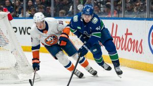 Vancouver Canucks' Quinn Hughes (right) skates with the puck while pressured by New York Islanders' Simon Holmstrom during third period NHL hockey action in Vancouver, B.C., Thursday, November 14, 2024. (Rich Lam/CP)