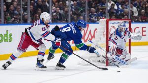 Vancouver Canucks' Conor Garland (8) is checked by New York Rangers' Vincent Trocheck (16) as he attempts a shot against goalie Igor Shesterkin (31) during third period NHL hockey action in Vancouver, B.C., Tuesday, Nov. 19, 2024. (Darryl Dyck/CP)