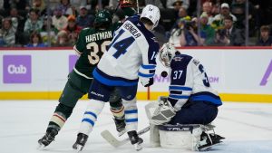 Winnipeg Jets goaltender Connor Hellebuyck (37) and defenceman Ville Heinola (14) defend against Minnesota Wild right wing Ryan Hartman (38) during the third period of an NHL hockey game, Monday, Nov. 25, 2024, in St. Paul, Minn. (Abbie Parr/AP)