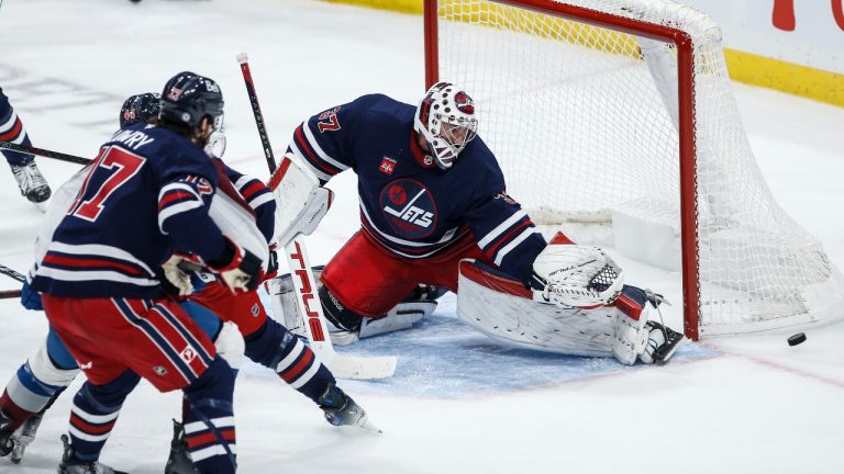 Winnipeg Jets goaltender Connor Hellebuyck (37) saves a shot from Colorado Avalanche's Calvin de Haan (44) as Adam Lowry (17) defends during third period NHL action in Winnipeg on Thursday, November 7, 2024. (John Woods/CP)