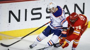 Edmonton Oilers' Travis Dermott, left, is checked by Calgary Flames' Martin Pospisil during third period NHL hockey action in Calgary on Sunday, Nov. 3, 2024. (Jeff McIntosh/CP Photo)