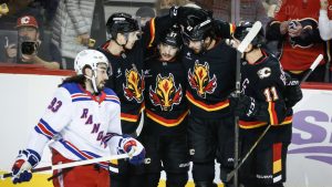 New York Rangers' Mika Zibanejad, left, skates past as Calgary Flames' Matthew Coronato (27) celebrates his goal with teammates during first period NHL hockey action in Calgary on Thursday, Nov. 21, 2024. (Jeff McIntosh/CP)