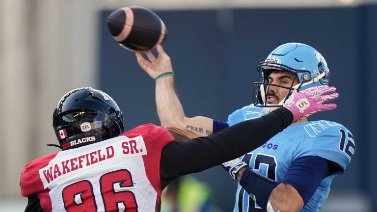 Toronto Argonauts quarterback Chad Kelly (12) makes a throw downfield as Ottawa Redblacks defensive lineman Michael Wakefield (96) defends during first half CFL football action in Toronto. (Frank Gunn/THE CANADIAN PRESS)