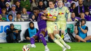 Orlando City forward Iván Angulo, left, is defended New York Red Bulls midfielder Peter Stroud, middle, and forward Cameron Harper, right, during the first half of an MLS Eastern Conference final soccer match. (Kevin Kolczynski/AP)