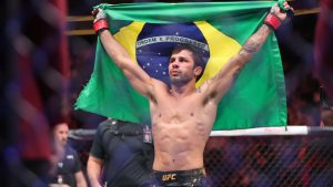 UFC flyweight champion Alexander Pantoja poses with the flag of Brazil after going five rounds against Brandon Royval during the UFC 296 mixed martial arts event Saturday, Dec. 16, 2023, in Las Vegas. Pantoja retained his title by unanimous decision. (Steve Marcus/Las Vegas Sun via AP)