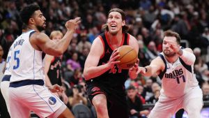 Toronto Raptors' Kelly Olynyk (41) drives between Dallas Mavericks' Quentin Grimes (5) and Luka Doncic (77) during first half NBA basketball action in Toronto on Saturday, Dec. 7, 2024. (Nathan Denette/CP)