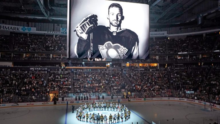 The Pittsburgh Penguins and Anaheim Ducks gather at center ice, before an NHL hockey game in Pittsburgh, Monday, Oct. 30, 2023, to honor former Penguin player Adam Johnson, shown on scoreboard, who died in while playing in an English hockey league game. (Gene J. Puskar/AP)