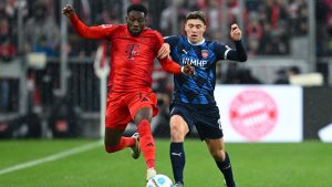 Munich's Alphonso Davies, left and Heidenheim's Luca Kerber, right, challenge for the ball during the German Bundesliga soccer match between FC Bayern Munich and 1. FC Heidenheim 1846 in Munich, Germany, Saturday, Dec. 7, 2024. (Sven Hoppe/dpa via AP)