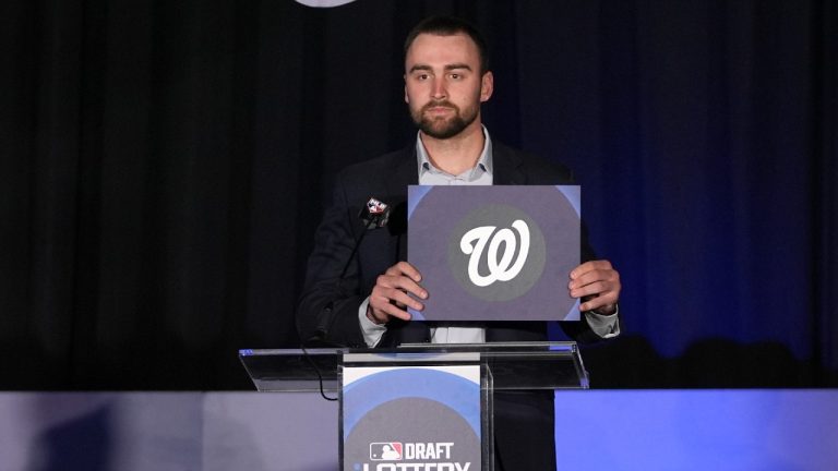 Emcee, Baltimore Orioles outfielder Colton Cowser, holds up the the Washington Nationals logo after the organization won the overall number one pick in the draft lottery at the Major League Baseball winter meetings in Dallas, Tuesday, Dec. 10, 2024. (Tony Gutierrez/AP)