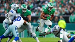 Philadelphia Eagles running back Saquon Barkley, centre, leaps as Dallas Cowboys linebacker Marist Liufau tries to trip him up during the second half of an NFL football game, Sunday, Dec. 29, 2024, in Philadelphia. (Matt Slocum/AP)