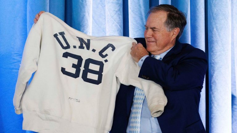 New North Carolina coach Bill Belichick holds up a sweatshirt that belonged to his father when he was on the coaching staff at UNC, Thursday, Dec. 12, 2024, during an NCAA college football press conference in Chapel Hill, N.C. (AP/Ben McKeown)