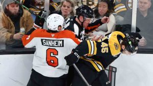 Referee Brandon Schrader, center, gets caught between Boston Bruins' Cole Koepke (45) and Philadelphia Flyers Travis Sanheim during an NHL hockey game, Saturday, Dec. 7, 2024, in Boston. (Jim Davis/AP)