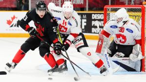 Canada's Tanner Howe (23) battles with Switzerland's Nils Rhyn (14) as goaltender Elijah Neuenschwander (30) looks on during second period IIHF World Junior Hockey Championship pre-tournament action in Ottawa on Thursday, December 19, 2024. THE CANADIAN PRESS/Sean Kilpatrick