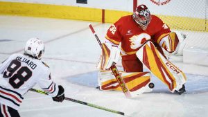 Chicago Blackhawks' Connor Bedard, left, has his shot stopped Calgary Flames goalie Dustin Wolf during first period NHL hockey action in Calgary, Alta., Saturday, Dec. 21, 2024. (Jeff McIntosh/CP)