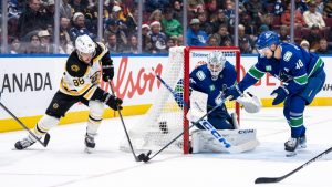 Boston Bruins' David Pastrnak (88) and Vancouver Canucks' Elias Pettersson (40) vie for the puck as goaltender Thatcher Demko (35) watches during the second period of an NHL hockey game in Vancouver, B.C., Saturday, Dec. 14, 2024. (Ethan Cairns/CP)