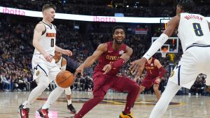 Cleveland Cavaliers guard Donovan Mitchell, center, passes the ball as Denver Nuggets guard Christian Braun, left, and forward Peyton Watson defend in the second half of an NBA basketball game Friday, Dec. 27, 2024, in Denver. (AP Photo/David Zalubowski)