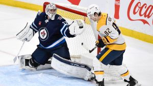 Winnipeg Jets goaltender Connor Hellebuyck makes a save on a Nashville Predators shot as Tommy Novak looks for the rebound during the third period of their NHL game in Winnipeg, Monday, Dec. 30, 2024. (THE CANADIAN PRESS/Fred Greenslade)