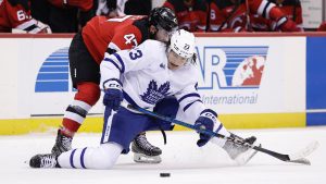 Toronto Maple Leafs left wing Matthew Knies (23) falls to the ice battling for the puck with New Jersey Devils centre Paul Cotter during the first period of an NHL hockey game Tuesday, Dec. 10, 2024, in Newark, N.J. (Adam Hunger/AP)