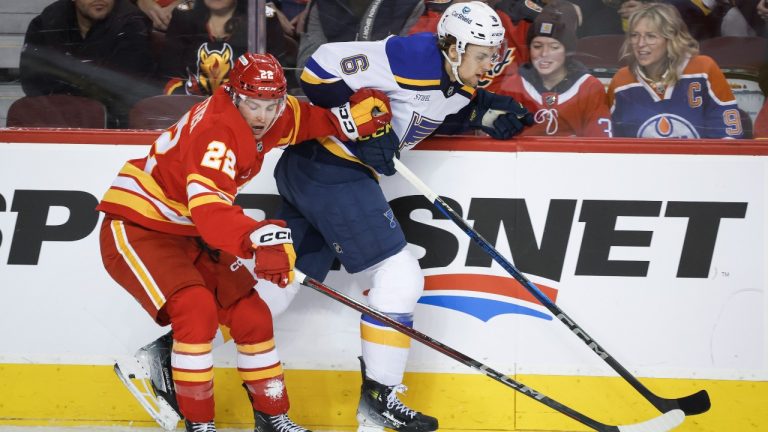 St. Louis Blues' Philip Broberg, right, is checked by Calgary Flames' Jakob Pelletier during first period NHL hockey action in Calgary on Thursday, Dec. 5, 2024. (Jeff McIntosh/CP)