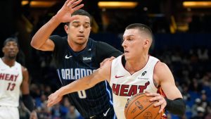 Miami Heat guard Tyler Herro, right, drives around Orlando Magic guard Anthony Black (0) during the first half of an NBA basketball game, Saturday, Dec. 21, 2024, in Orlando, Fla. (AP Photo/John Raoux)