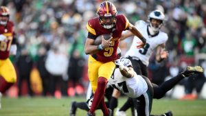 Washington Commanders quarterback Jayden Daniels (5) breaks away from Philadelphia Eagles linebacker Nakobe Dean (17) and runs with the ball during the second half of an NFL football game, Sunday, Dec. 22, 2024, in Landover, Md. (Nick Wass/AP)