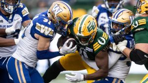 Winnipeg Blue Bombers' Evan Holm (31) and Brandon Alexander (37) tackle Edmonton Elks' Kevin Brown (centre) in Edmonton, on Saturday September 21, 2024. (Jason Franson/CP)