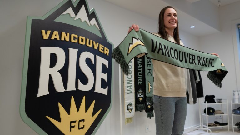 Shannon Woeller poses with a Vancouver Rise FC scarf during a news conference to announce her as the first player to join the organization in Vancouver, B.C., Monday, Dec. 16, 2024. (THE CANADIAN PRESS/Ethan Cairns)