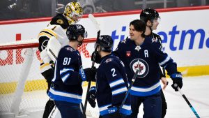 Winnipeg Jets' Kyle Connor (81) celebrates his goal against the Boston Bruins with Mark Scheifele (right) and Dylan Demelo (2) during the third period of their NHL hockey game in Winnipeg, Tuesday December 10, 2024. (Fred Greenslade/CP)