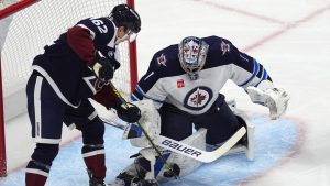 Winnipeg Jets goaltender Eric Comrie, right, stops a redirected shot by Colorado Avalanche left wing Artturi Lehkonen in the first period of an NHL hockey game Tuesday, Dec. 31, 2024, in Denver. (David Zalubowski/AP)