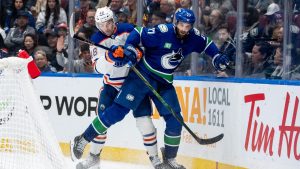 Edmonton Oilers' Luke Philp (48) and Vancouver Canucks' Derek Forbort (27) vie for the puck during third period NHL pre-season hockey action in Vancouver, on Friday, October 4, 2024. (Ethan Cairns/CP)