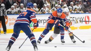 Vegas Golden Knights' Alexander Holtz (26) and Edmonton Oilers' Leon Draisaitl (29) battle for the puck during third period NHL action in Edmonton, Saturday, Dec. 14, 2024. (Jason Franson/CP)